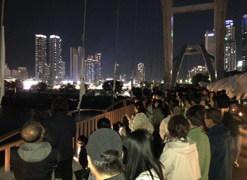 울산공업축제 낙화놀이를 구경 나온 관람객들이 태화강 국가정원 십리대밭교 난간에 붙어있다. 인도교인 이 다리는 길이 120m, 폭 4~5m인데 1000명 가까운 인파가 낙화놀이가 펼쳐지는 방향의 다리 난간으로 쏠리면서 위험한 상황을 연출했다. 분산 이동을 요청하는 안내 방송이 수차례 나왔지만 분산은 이뤄지지 않았다. 사진=최수상 기자