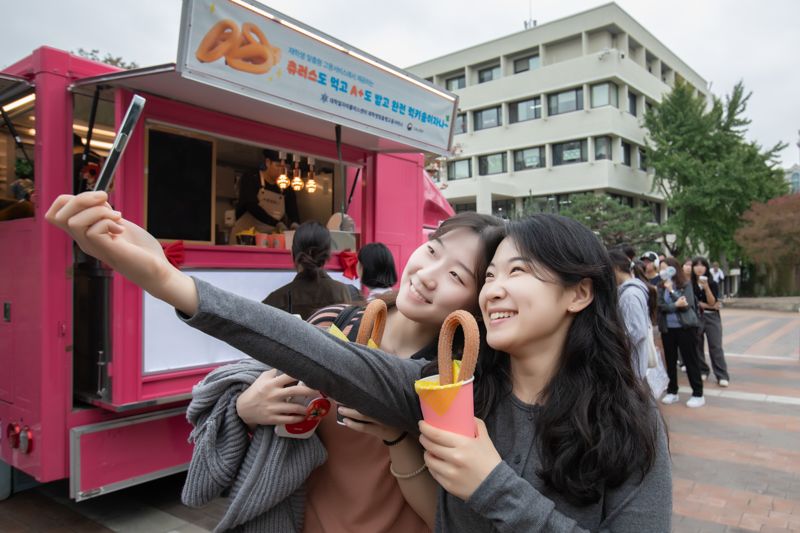 숙명여대 대학일자리플러스센터가 지난 15일 오후 교내 순헌관광장에서 진행한 '재학생 맞춤형 고용서비스' 홍보 행사에서 학생들이 추로스를 들고 사진을 찍고 있다. 숙명여대 제공