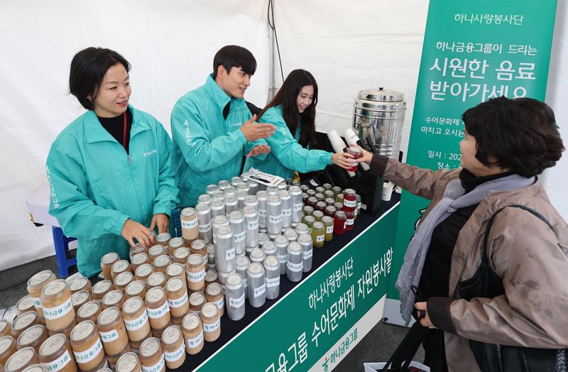 하나금융그룹 임직원들이 지난 22일 서울 광화문광장에서 열린 ‘수어문화제’에 참여했다. 이날 자원봉사활동에 참여한 그룹 임직원들이 하나금융그룹 부스를 찾은 농인과 가족들에게 음료를 나눠주며 수어로 인사하고 있다. 하나금융그룹 제공