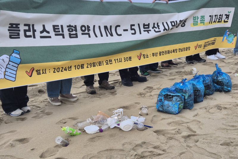 [부산=뉴시스] 김민지 기자 = 29일 오전 부산 광안리해수욕장에서 개최된 '플라스틱협약 부산시민행동' 출범 기자회견에서 현수막 앞에 놓인 각종 쓰레기와 플라스틱. 2024.10.29. mingya@newsis.com