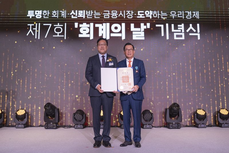 김영식 전 삼일회계법인 대표이사(오른쪽)가 10월 31일 열린 '제7회 회계의 날' 행사에서 철탑산업훈장을 수상한 후 김병환 금융위원장과 기념촬영을 하고 있다. 삼일회계법인 제공.