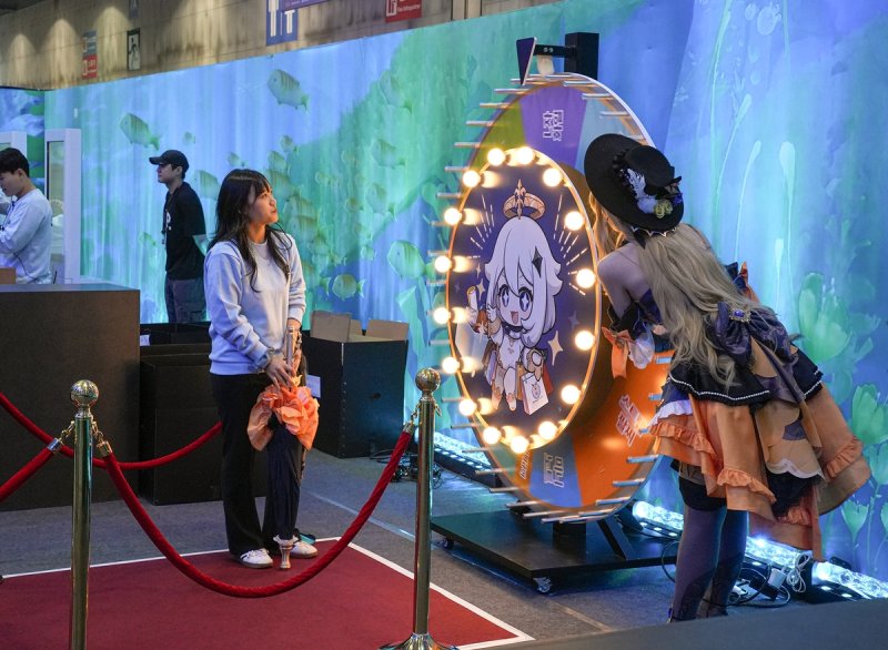 미니게임 즐기는 코스튬 플레이어 (고양=연합뉴스) 김주환 기자 = 31일 오전 경기 고양시 킨텍스에서 호요버스코리아가 개최한 '웰컴 호요랜드' 행사장 내 '원신' 부스에서 게임 캐릭터로 코스프레를 한 관람객이 돌림판 미니게임을 즐기고 있다. 2024.10.31 jujuk@yna.co.kr