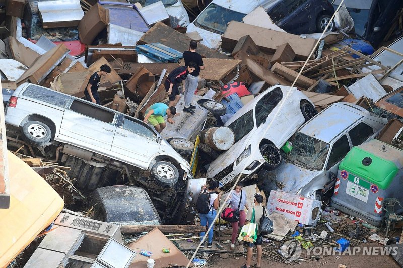스페인 대홍수 TOPSHOT - Persons climb on piled up cars following floods in Sedavi, south of Valencia, eastern Spain, on October 30, 2024. Floods triggered by torrential rains in Spain's eastern Valencia region has left at least 70 people dead, rescue services said on October 30. (Photo by Jose Jordan / AF