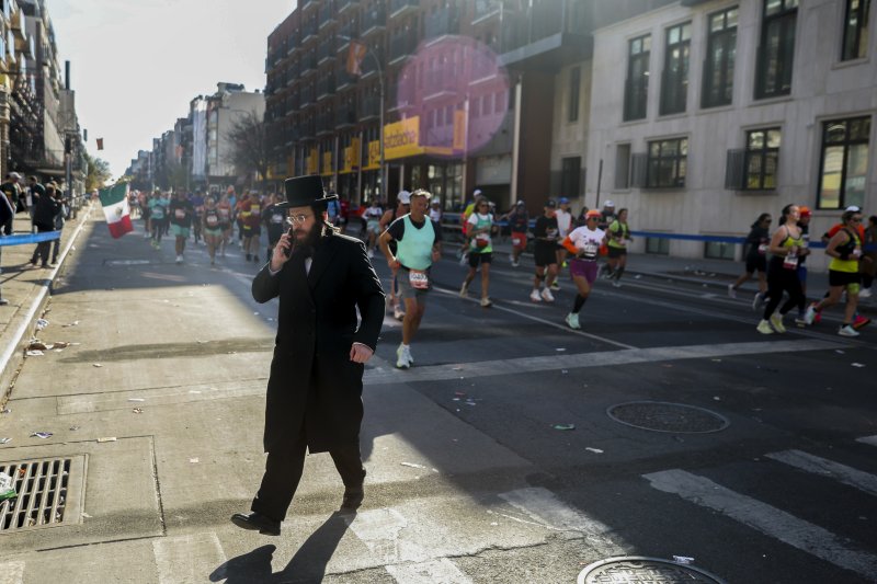 [뉴욕=AP/뉴시스] 3일(현지시각) 미국 뉴욕에서 제54회 뉴욕 마라톤이 열려 주자들이 달리는 가운데 한 정통 유대교 남성이 휴대전화 통화를 하며 주로를 가로지르고 있다. 세계 6대 마라톤 중 하나인 뉴욕 마라톤은 매년 11월 첫째 일요일에 열린다. 2024.11.04.