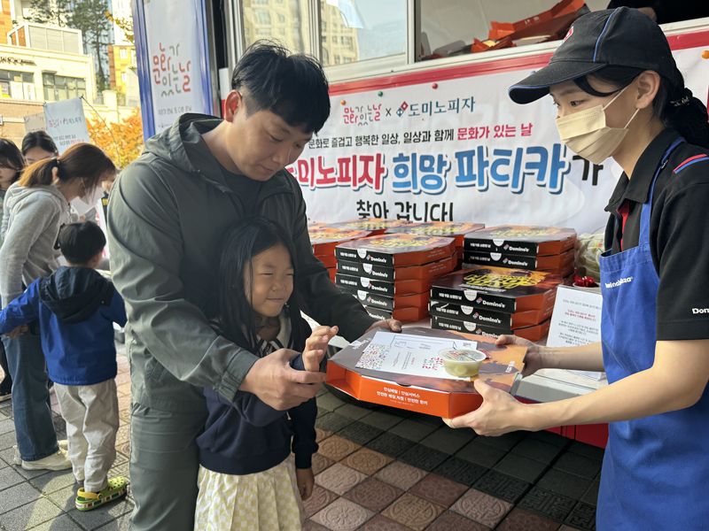 최근 세종시 고운동 도서관에서 열린 '책을 피자 이벤트'에서 독서 쿠폰을 획득한 한 가족 회원이 피자를 전달 받고 있다. 도미노피자 제공