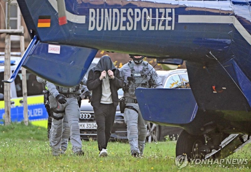 체포된 용의자 Policemen escort a man, one of eight suspected members of a militant group, after he was heard at the Federal Court of Justice towards a helicopter in Karlsruhe, southern Germany, on November 5, 2024. German police arrested eight suspected members of a right-wing extremist group that had tra