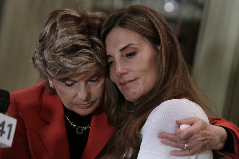 【뉴욕=AP/뉴시스】20일(현지시간) 미국 뉴욕에서 열린 기자회견에서 공화당 도널드 트럼프 후보로부터 과거 성추행을 당했다고 주장한 요가 강사카레나 버지니아(45)가 동석한 변호사와 포옹하고 있다. 버지니아는 1998년 US오픈 테니스 경기를 관람하러 갔을 때 트럼프가 자신을 성추행했다고 밝혔다. 2016.10.21