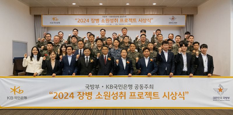 지난 7일 서울시 용산구 국방컨벤션에서 열렸던 ‘2024 장병소원성취 프로젝트’시상식에서 윤봉희 국방부 정책기획관(첫째줄 왼쪽 다섯 번째)과 서영익 KB국민은행 기관영업그룹대표(첫째줄 왼쪽 여섯 번째)가 수상자들과 함께 기념촬영을 하고 있다. KB국민은행 제공