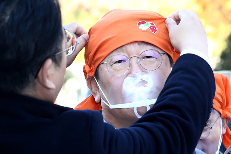 22일 오후 서울 여의도 국회에서 열린 2024대한민국 김치대전에 참가한 이재명 더불어민주당 대표의 머리수건을 관계자가 바로잡아주고 있다. 2024.11.22/뉴스1 ⓒ News1 이광호 기자