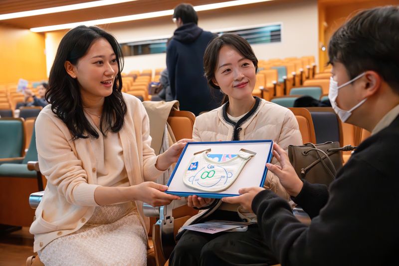 지난 22일 오후 광화문 교보생명 본사 23층 대산홀에서 열린 ‘찾아가는 음악회’에 참석한 임산부들이 스마일 턱받이를 건네 받고 있다. 사진=교보생명 제공