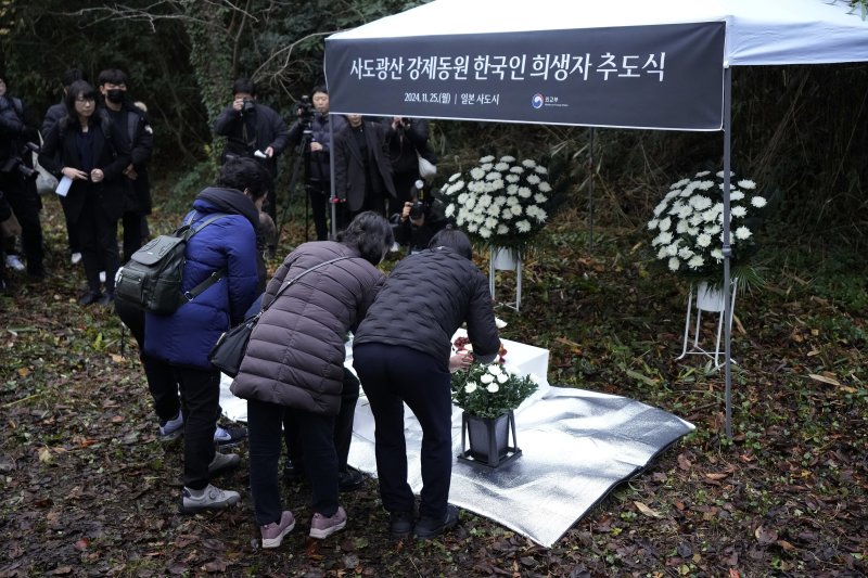 [사도=AP/뉴시스] 25일 일본 니가타현 사도 광산 인근 조선인 기숙사 터에서 일본 정부와 별도로 사도 광산 강제동원 한국인 희생자 추도식이 열려 희생자 유족들이 헌화하고 있다. 2024.11.25.