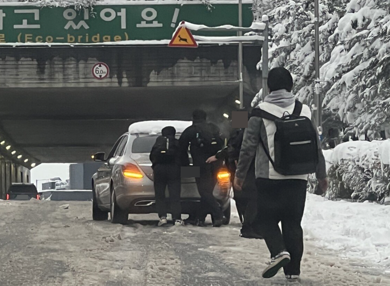 경기 시흥 소재의 한 터널 앞에서 눈길에 도로를 오르지 못하는 차량을 발견한 학생들이 뒤에서 밀어 도와주고 있다./사진=온라인 커뮤니티 '에펨코리아'