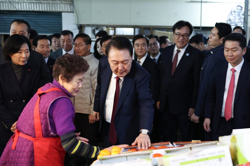 윤석열 대통령이 2일 충남 공주시 공주산성시장을 찾아 감을 살펴보고 있다. (사진=대통령실 제공) /사진=뉴시스화상