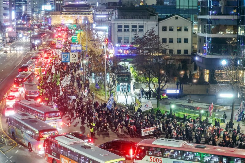 시민사회단체 관계자들이 4일 오후 서울 종로구 동화면세점 앞에서 윤석열 대통령의 퇴진을 촉구하는 촛불집회를 마친 뒤 대통령실 방향으로 행진하고 있다. 뉴스1