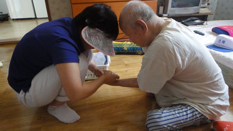 한센인 장기진씨(오른쪽)의 손톱을 깎고 있는 간호조무사. 장씨는 경북 청송 태생으로 지난 1941년에 입도했다. 전경수 교수 제공
