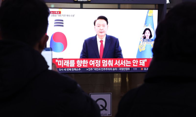 윤석열 대통령의 탄핵소추안이 국회에서 가결된 지난 14일 오후 서울역에서 시민들이 윤석열 대통령의 대국민 담화를 TV를 통해 지켜보고 있다. 연합뉴스