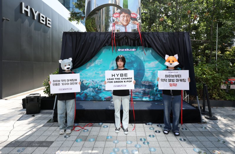[서울=뉴시스] 김선웅 기자 = 전 세계 K-POP 팬들이 결성한 '케이팝포플래닛'이 자원순환의 날(9월 6일)을 앞둔 4일 서울 용산구 하이브 본사 앞에서 국내 엔터테인먼트사들의 실물 음반 생산 및 폐기를 야기하는 마케팅 중단을 촉구하고 있다. 케이팝포플래닛은 엔터 기업들이 실물 앨범에 무작위 포토카드, 팬 사인회 응모권 포함, 표지만 다른 동일 앨범을 발매해 팬들이 여러 장의 실물 음반을 사도록 부추긴다고 말하며 이러한 화석연료 기반 소재의 앨범은 기후위기를 악화시키고 대부분 재활용없이 폐기돼 플라스틱 오염 문제를 야기하므로 '