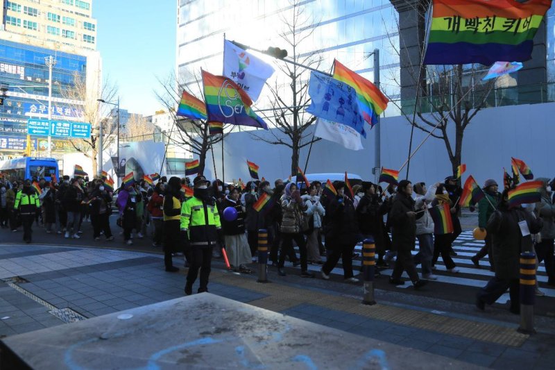 22일 오후 부산 부산진구 서면 일원에서 '2024 메리퀴어스마스' 행사 참가자들이 깃발을 들고 행진하고 있다.(청년인권단체 아수나로 제공)