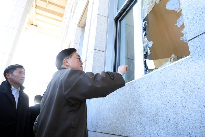 우원식 국회의장이 지난해 12월 4일 국회 내부로 계엄군이 진입하며 깨뜨린 국민의힘 정책위의장실 유리 창문을 바라보고 있다. 뉴시스