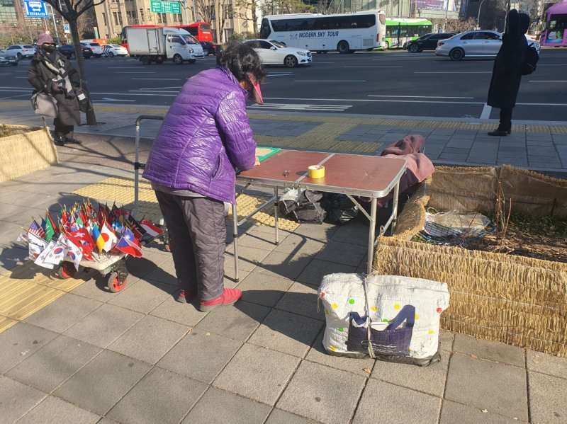 23일 오후 서울 종로구 동화면세점 앞에서 만난 노점상 A씨. 태극기와 성조기 등 국기를 판매할 준비를 하고 있다. 사진=최승한 기자