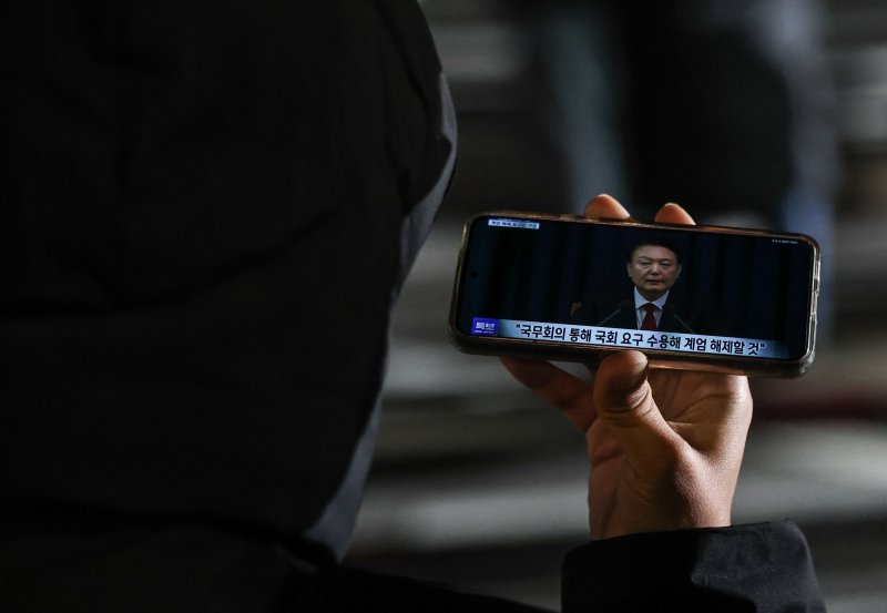 [서울=뉴시스] 김명년 기자 = 윤석열 대통령이 국회 계엄해제령 관련해 담화문을 발표한 가운데 4일 새벽 서울 여의도 국회 인근에서 한 시민이 생중계를 지켜보고 있다. 2024.12.04. kmn@newsis.com