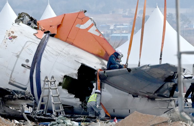 [무안=뉴시스] 김혜인 기자 = 15일 오전 제주항공 여객기 참사가 발생한 무안공항에서 사고 여객기 잔해 수습에 앞서 꼬리 동체를 중장비에 연결하는 작업을 하고 있다. 2025.01.15. hyein0342@newsis.com