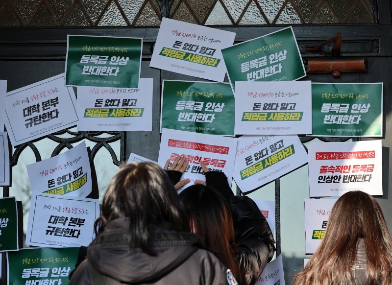 [서울=뉴시스] 이영환 기자 = 이화여자대학교 학생들이 17일 오후 서울 서대문구 이화여자대학교 정문에서 등록금 인상 반대하는 이화인 3239인 서명 전달 기자회견을 마친 후 본관으로 행진해 문이 닫혀 있자 피켓을 붙이고 있다. 2025.01.17. 20hwan@newsis.com