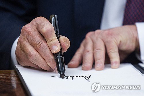 트럼프 대통령이 취입 첫날 행정명령에 서명하는 모습 (출처=연합뉴스)