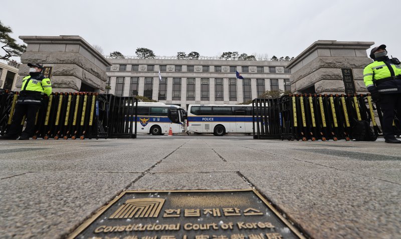 '내란 우두머리' 혐의를 받는 윤석열 대통령이 구속기소 되면서 현직 대통령이 탄핵 심판과 형사 재판을 동시에 받는 초유의 사태가 현실화했다. 탄핵심판은 앞으로 매주 2회씩 오는 6일부터는 오전부터 저녁까지 종일 열린다. 내란 우두머리 혐의에 대한 형사재판은 서울중앙지법에서 열리며 이르면 31일 재판부를 배당하고 2월 중 공판준비절차를 거쳐 3월에는 본 재판에 나설것으로 보인다. 사진은 31일 서울 종로구 헌법재판소에서 경찰들이 경계근무를 서고 있는 모습. 2025.1.31/뉴스1 ⓒ News1 김도우 기자