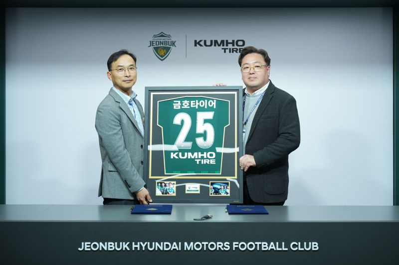 금호타이어 G.마케팅담당 윤민석 상무(왼쪽)와 전북현대모터스 이도현 단장이 공식 파트너십 연장 조인식을 체결하며 금호타이어 로고가 적용된 유니폼 액자를 들고 기념사진을 찍고 있다. 금호타이어 제공
