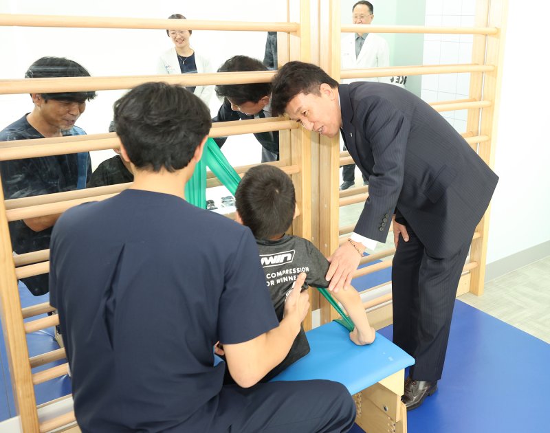 하나금융그룹은 장애인의 건강한 성장과 경제적 자립을 위한 생애주기별 맞춤형 통합 지원 사업을 실시한다고 밝혔다. 이번 사업의 첫 시작으로 지난 17일 서울 마포구 소재 푸르메재단 넥슨어린이재활병원에서 ‘장애 아동ㆍ청소년을 위한 재활 및 학습 보조기구 전달식’을 가졌다. 이날 전달식에 참석한 함영주 회장(사진 맨 오른쪽)이 중추신경계 발달치료를 받고 있는 장애 아동에게 따뜻한 격려의 말을 전하고 있다. (하나금융그룹 제공)