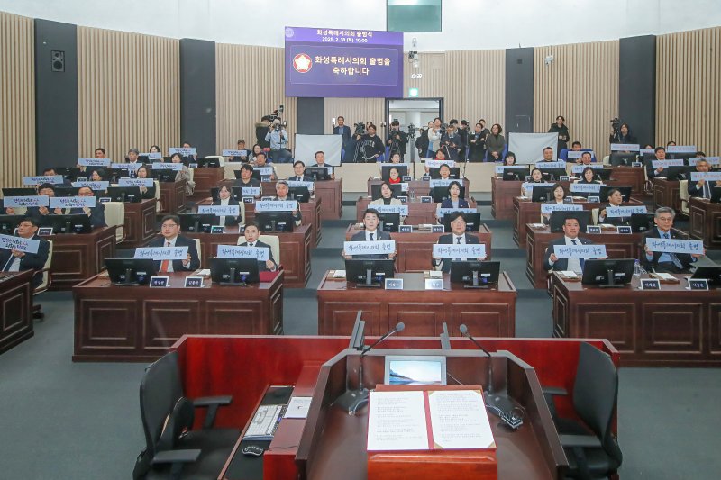 [화성=뉴시스] 화성시의회 의원들이 18일 본회의장에서 제239회 임시회 시작에 앞서 '화성특례시의회 출범'이라는 피켓을 들고 특례시의회 출범을 자축하고 있다. (사진=화성시의회 제공) 2025.02.18. photo@newsis.com