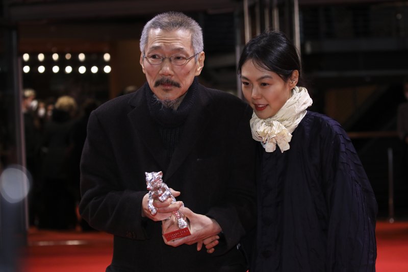 [베를린=AP/뉴시스] 홍상수 감독이 16일(현지시간) 독일 베를린에서 열린 제72회 베를린국제영화제 시상식에서 영화 '소설가의 영화'로 은곰상 심사위원대상을 받고 연인인 배우 김민희와 함께 포즈를 취하고 있다. 2022.02.16.