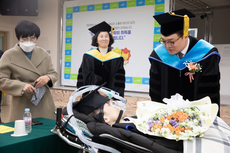 [광주=뉴시스] 광주대 김동진(사진 오른쪽) 총장이 지난 21일 사회복지전문대학원 석사학위를 받은 근육장애인 졸업생 장익선(37)씨를 찾아 축하인사를 건네고 있다. (사진 = 광주대 제공). 2025.02.23. photo@newsis.com *재판매 및 DB 금지