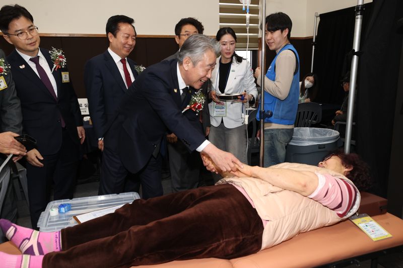 강호동 농협중앙회장(오른쪽 세번째)이 25일 경북 안동시 일직중학교에서 농업인을 대상으로 진행한 ‘농촌 왕진버스’의 의료 서비스를 받고 있는 농업인과 손을 맞잡고 인사하고 있다. 농협중앙회 사진 제공