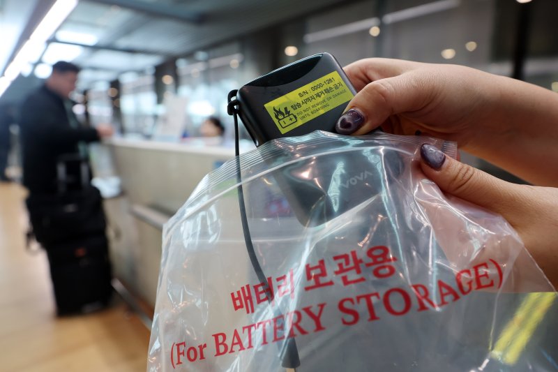 [서울=뉴시스] 김명년 기자 = 1일 인천국제공항 제2여객터미널 대한항공 체크인 카운터에서 관계자가 보조배터리에 스티커를 부착한 뒤 비닐봉지에 넣고 있다. 국토교통부는 이날부터 보조배터리와 전자담배 안전관리 체계 강화 표준안을 시행한다 2025.03.01. kmn@newsis.com