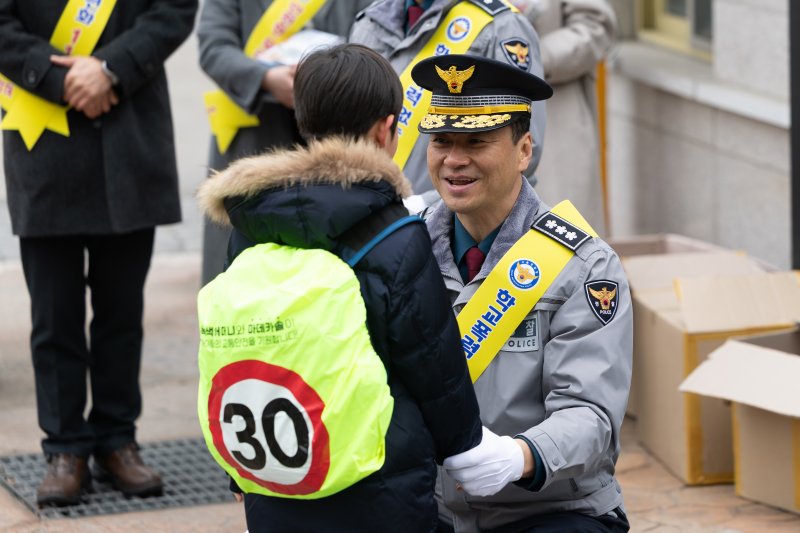 박현수 서울지방경찰청장 직무대리가 5일 오전 서울 서대문구 고은초등학교앞에서 열린 신학기 안전한 학교 만들기 캠페인에 참석해 학생에게 스쿨존 속도제한 레인커버를 씌워준 뒤 대화하고 있다. 2025.3.5/뉴스1 ⓒ News1 이승배 기자