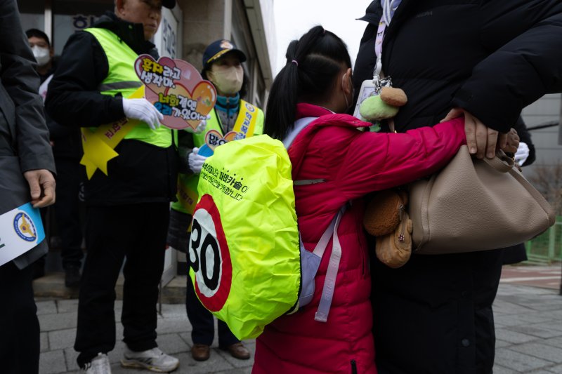 5일 오전 서울 서대문구 고은초등학교앞에서 한 학생이 가방에 스쿨존 속도제한 레인커버를 덮고 있다. 2025.3.5/뉴스1 ⓒ News1 이승배 기자