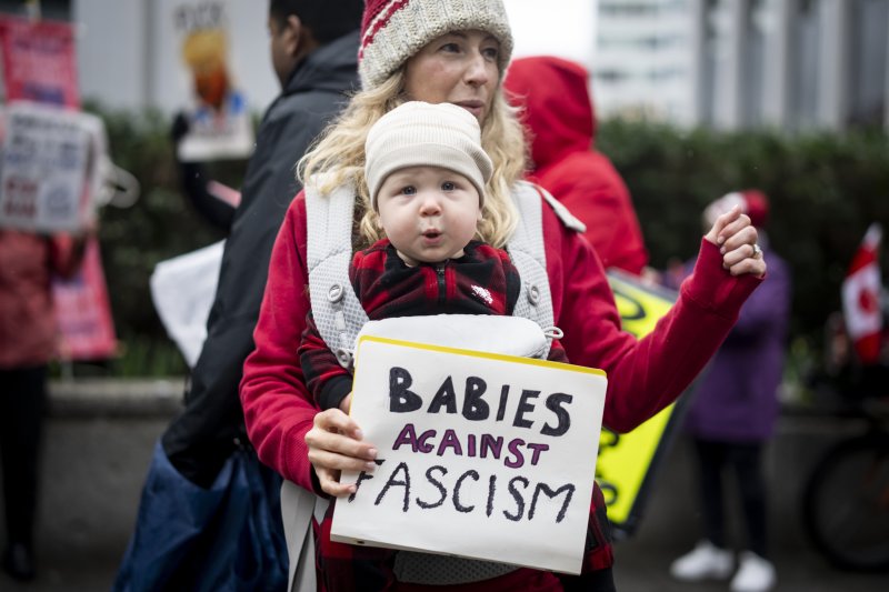 [밴쿠버=AP/뉴시스] 4일(현지 시간) 캐나다 브리티시컬럼비아주 밴쿠버에 있는 미국 대사관 앞에서 아이를 안은 여성이 손팻말을 들고 반미 시위를 하면서 춤추고 있다. 캐나다와 멕시코가 미국이 부과한 관세에 대응해 보복 관세 방침을 밝힌 가운데 도널드 트럼프 미국 대통령은 이에 추가 관세를 부과하겠다고 밝혔다. 2025.03.05.