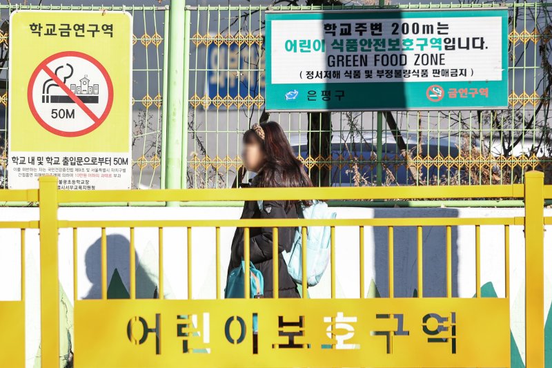 서울의 한 초등학교에 등교하는 어린이 위로 어린이 식품안전보호구역 안내 표지판이 설치돼 있다.2025.2.24/뉴스1 ⓒ News1 민경석 기자