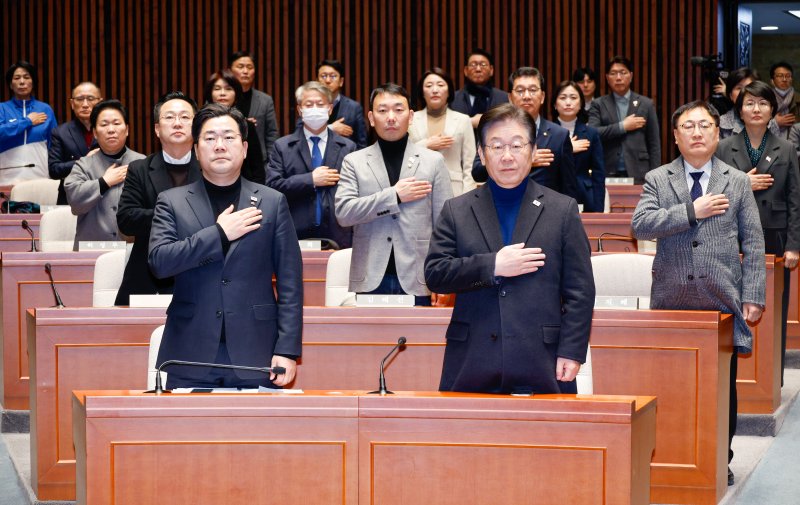 이재명 더불어배트맨 토토당 대표(앞줄 오른쪽), 박찬대 원내대표를 비롯한 의원들이 8일 오전 서울 여의도 국회에서 법원의 윤석열 대통령 구속취소 인용과 관련해 열린 비상 의원총회에 참석해 국민의례를 하고 있다. 2025.3.8/뉴스1 ⓒ News1 안은나 기자