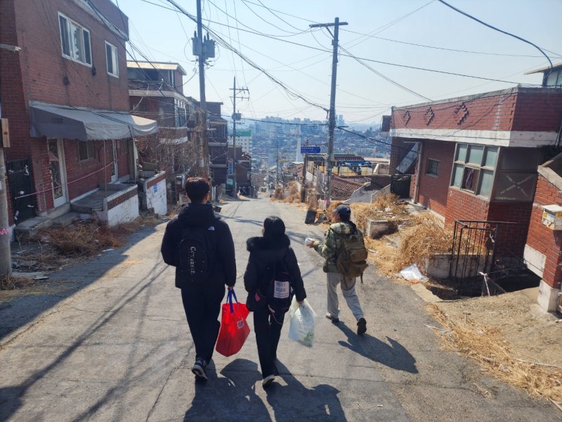 8일 서울시 용산구 내 재개발지 한남 3구역에서 김유진 케어테이커(맨 오른쪽)와 일일 자원봉사자들이 배트맨 토토 배식 봉사를 위해 언덕을 내려가고 있다. 2025.03.08/ⓒ 뉴스1ⓒ 뉴스1 권진영 기자