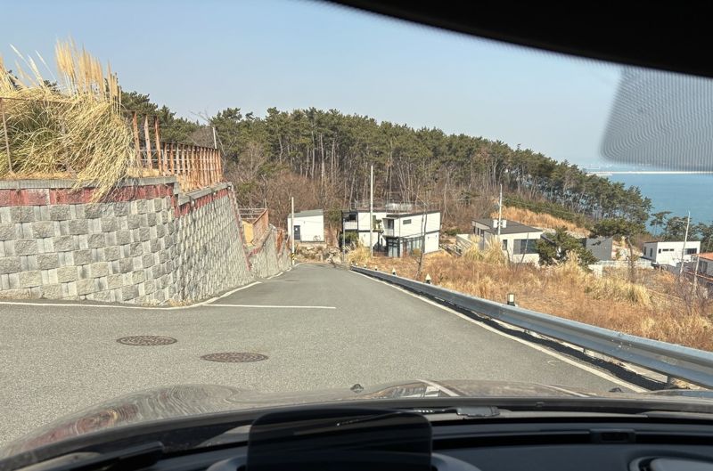 카페와 펜션으로 갈라지는 삼거리에서 바라본 택시 사고 현장 내리막길. 경사도 15% 안팎으로 추정된다. 사진 가운데 하얀 건물 앞이 사고 현장이다. 거리는 약 74m. 길은 일반적인 운전자라면 가속 페달을 밟을 수 없을 정도의 아찔한 내리막길이었다. 취재진도 안전을 위해 끝까지 브레이크 페달을 밟고 내려갔다. 사진=최수상 기자