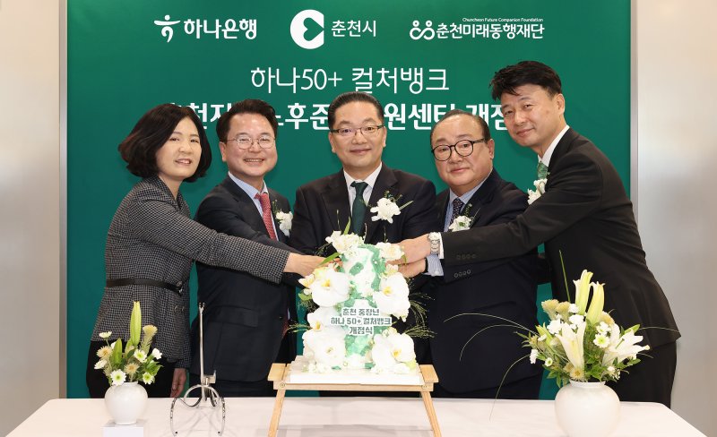 하나은행은 지난 18일 오전 강원도 춘천시 소재 하나은행 춘천지점에 중장년 세대를 위한 '춘천 하나50+컬처뱅크'를 개점했다. 이날 개점식에 참석한 이호성 하나은행장(가운데)과 육동한 춘천시장(왼쪽 두번째), 신용준 춘천미래동행재단 이사장(오른쪽 두번째), 배숙경 춘천시의회 부의장(왼쪽 첫번째), 박장석 하나은행 춘천지점장(오른쪽 첫번째)이 케이크 커팅을 하며 기념촬영을 하고 있다. 하나은행 제공
