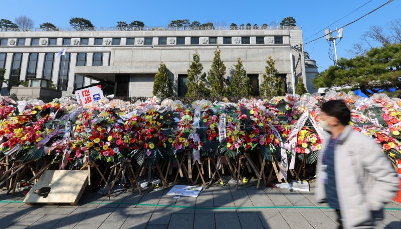 [서울=뉴시스] 이영환 기자 = 윤석열 대통령 탄핵심판 선고가 예상보다 늦어지고 있는 19일 오전 서울 종로구 헌법재판소 앞에 윤 대통령 지지자들이 보낸 화환이 놓여 있다.헌법재판소 사무처장이 지난 달 26일까지 자진 정비를 요청하며 적치물 정비 예고통지서를 부착했지만 화환은 방치되고 있다. 2025.03.19. 20hwan@newsis.com