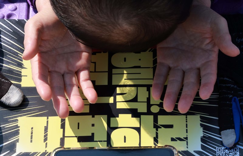 [서울=뉴시스] 고범준 기자 = 10.29 이태원 참사 유가족협의회, 시민대책회의 관계자들이 19일 서울 종로구 광화문 월대 옆에서 윤석열 대통령 파면 기원 159배를 하고 있다. 2025.03.19. bjko@newsis.com