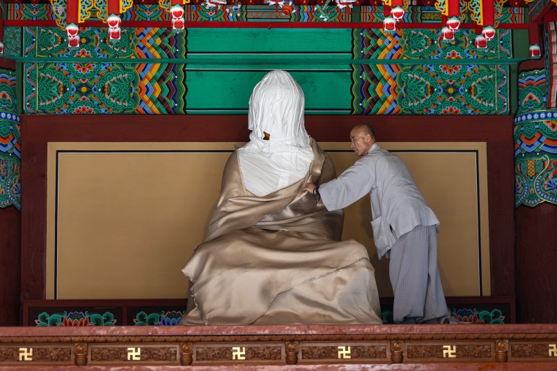 26일 경북 의성군 고운사 대웅전에서 스님이 불상에 씌운 방염포를 벗기고 있다. 이번 경북 의성 산불로 국가지정 문화유산 보물로 지정된 고운사 가운루와 연수전 등이 전소됐다. 2025.3.26/뉴스1 ⓒ News1 이승배 기자