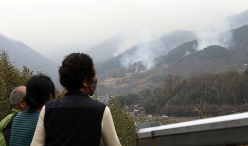 경남 산청·하동 산불 일주일째인 27일 오후 주민들이 지리산과 인접한 산청군 시천면 동당마을 위로 피어오르는 산불 연기를 지켜보고 있다. 산청에는 오후부터 5mm 내외의 적은 비가 예보됐지만 현재 비는 내리지 않고 있다. 2025.3.27/뉴스1 ⓒ News1 윤일지 기자