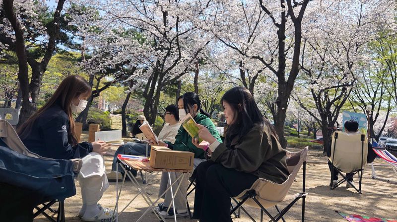 영진전문대 도서관이 만개한 벚꽃 숲 길에 마련한 북 피크닉을 학생들이 즐기고 있다. 영진전문대 제공