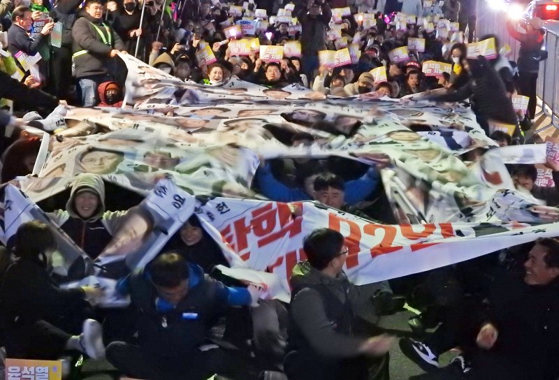 [제주=뉴시스] 오영재 기자 = 윤석열 대통령 탄핵 심판 선고 전날인 3일 오후 제주시청에서 열린 '윤석열 파면 촉구 제주도민대회'에서 주최 측인 윤석열정권퇴진 한국사회대전환 제주행동이 탄핵 반대 국회의원 92인의 현수막을 찢는 퍼포먼스를 하고 있다. 2025.04.03. oyj4343@newsis.com
